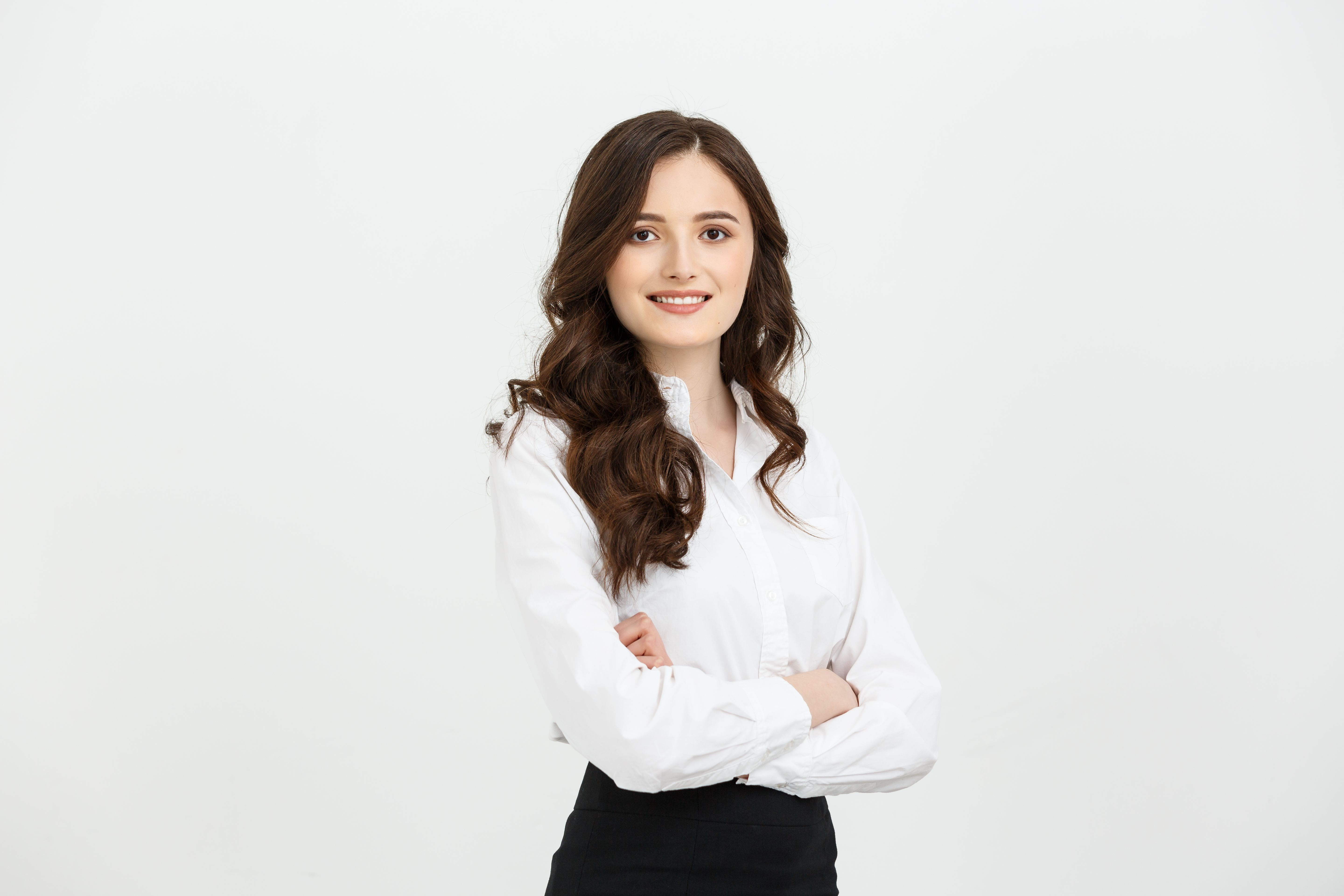 Smiling woman in a white blouse with arms crossed against a light background